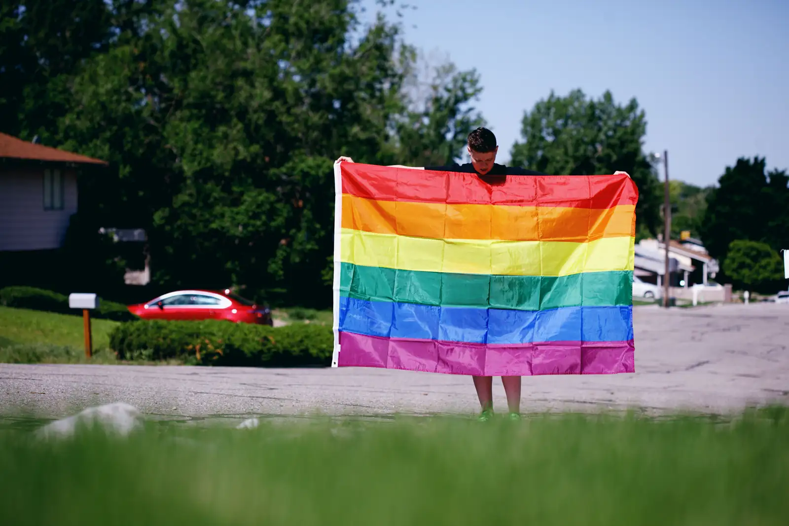 A person holding a large rainbow pride flag outdoors