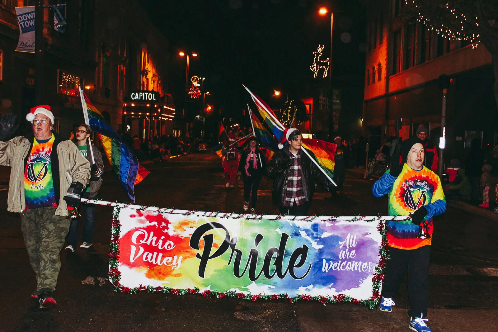 People marching in a pride parade with a banner