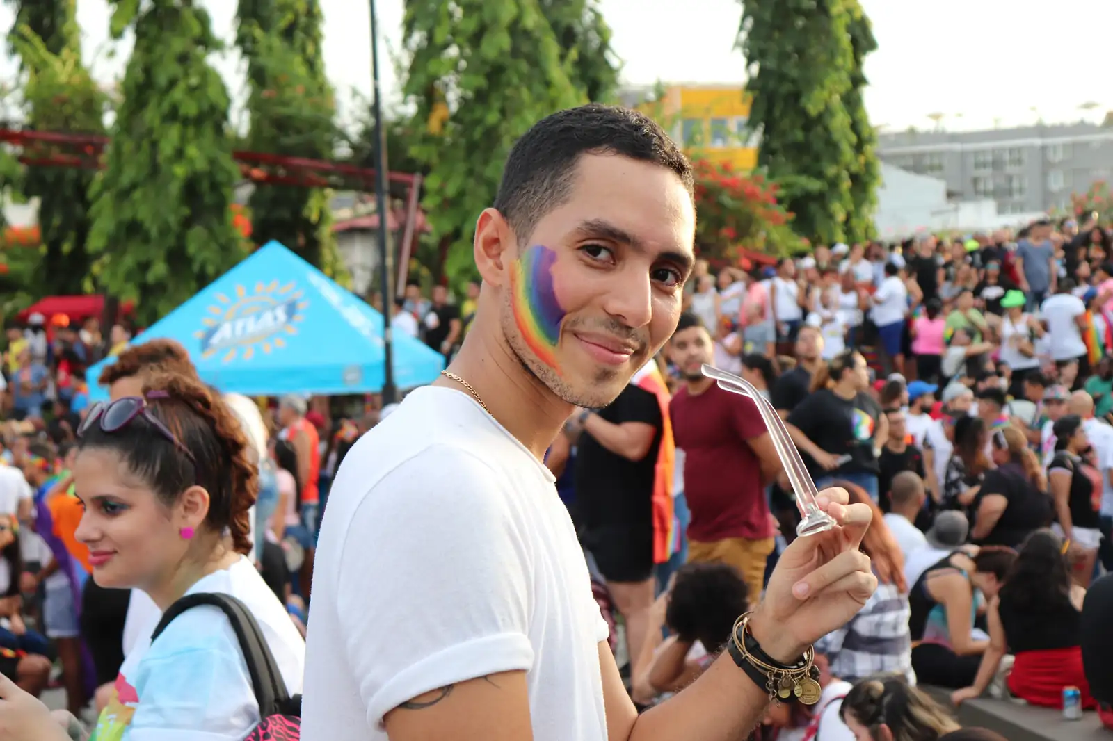 A parade participant with a rainbow painted on his face