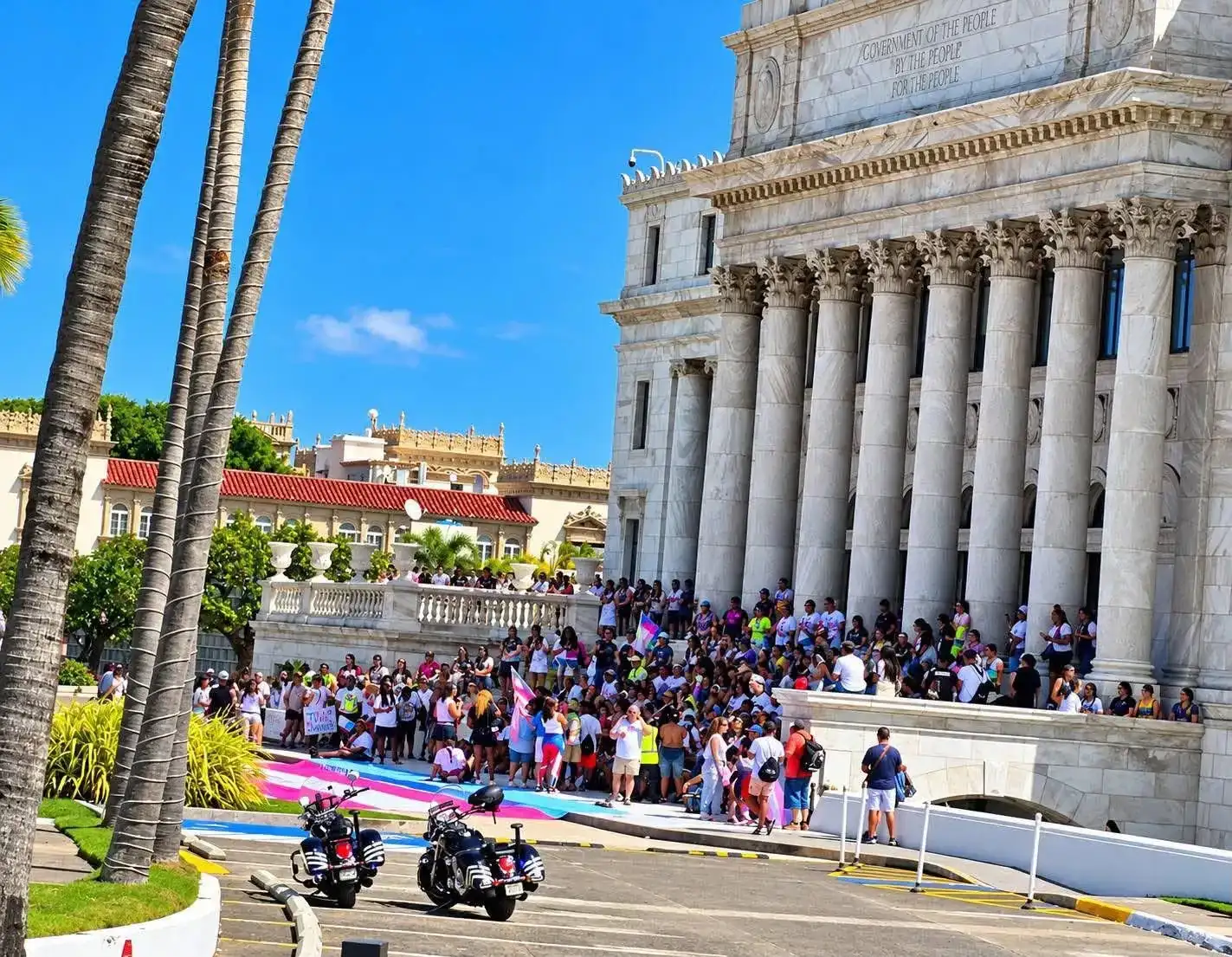 Marchers gather in front of the Puerto Rico Capitol with a giant transgender flag painted on the ground