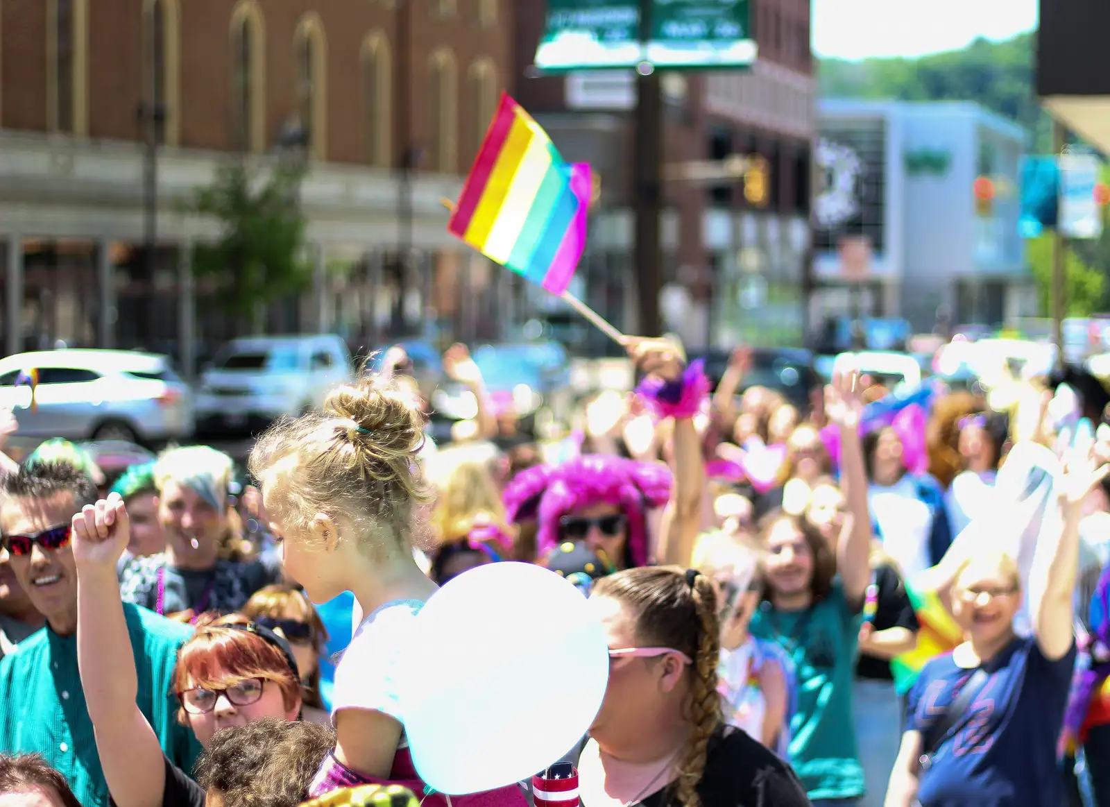 Crowds waving rainbow flags at a pride parade